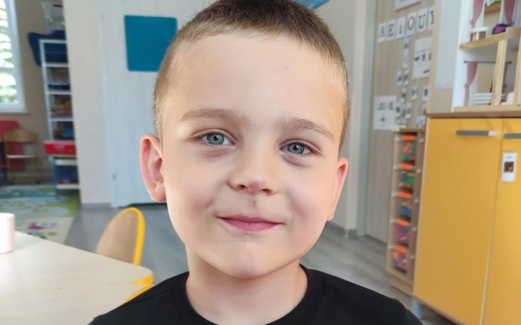 Chłopiec z uśmiechem, siedzący w przedszkolu.