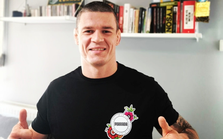 Mężczyzna w czarnej koszulce uśmiecha się, pokazując kciuki w górę.