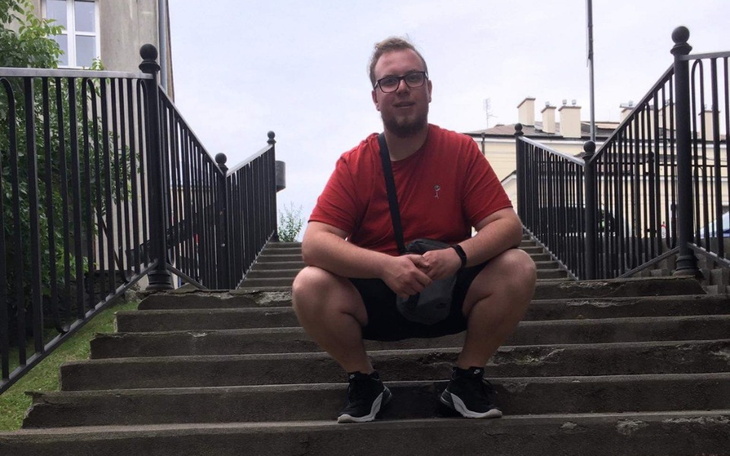 Mężczyzna w czerwonej koszulce siedzący na schodach.