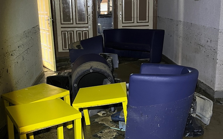 Zniszczone meble w opuszczonym pomieszczeniu, w tle drzwi.