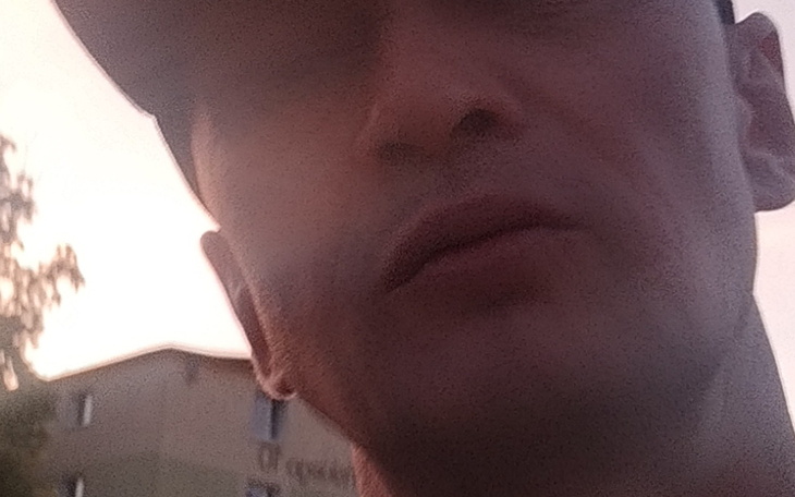 Nieostre zdjęcie mężczyzny w plenerze, z bliskim ujęciem twarzy.