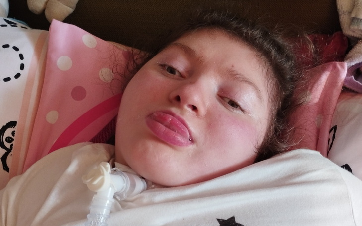 Dziewczynka leżąca na poduszce, pokazująca język.