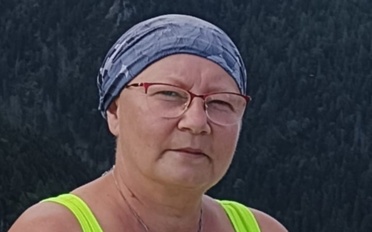 Kobieta w chustce na tle górskiego krajobrazu.