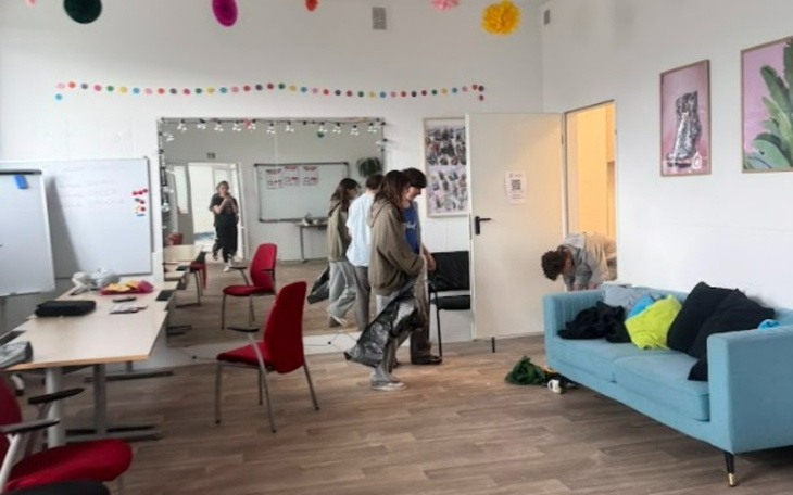 Wnętrze pokoju z osobami, meblami i lustrami.