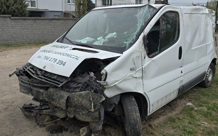 Zniszczony biały van na poboczu drogi.