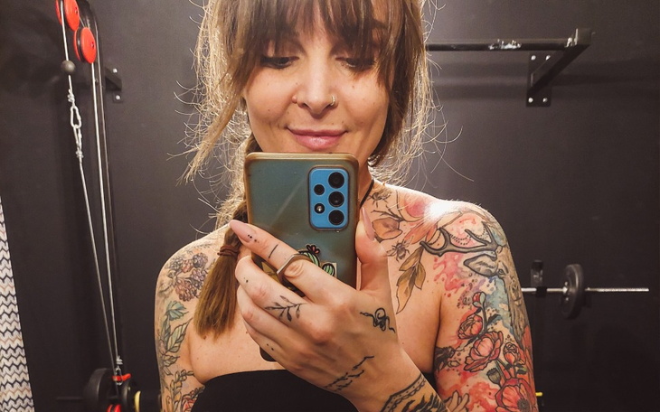 Kobieta z tatuażami, robiąca selfie w siłowni.