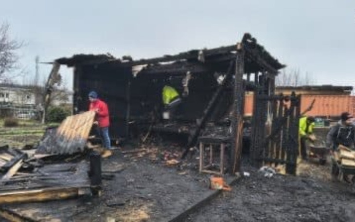 Zgliszcza po pożarze, ludzie sprzątający teren.