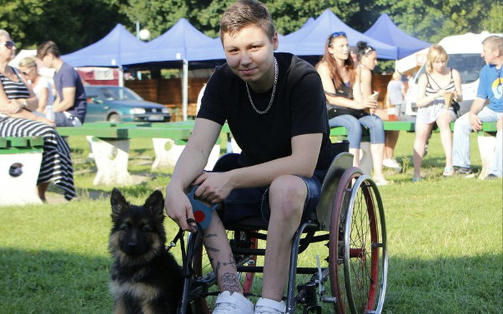 Młody chłopak na wózku inwalidzkim z psem.