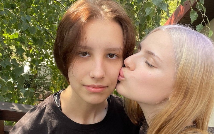 Dwie młode osoby, jedna całuje drugą w policzek.