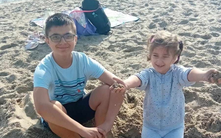 Dwoje dzieci bawiących się w piasku na plaży.