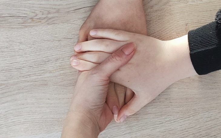 Ręce różnych osób trzymające się nawzajem na stole.