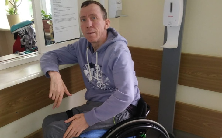 Mężczyzna na wózku inwalidzkim, uśmiechający się w poczekalni.