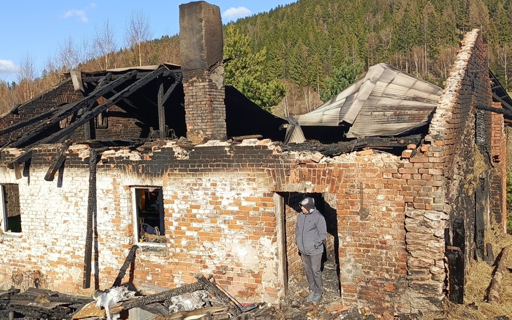 Zniszczony budynek z wypalonym dachem i ceglaną ścianą.