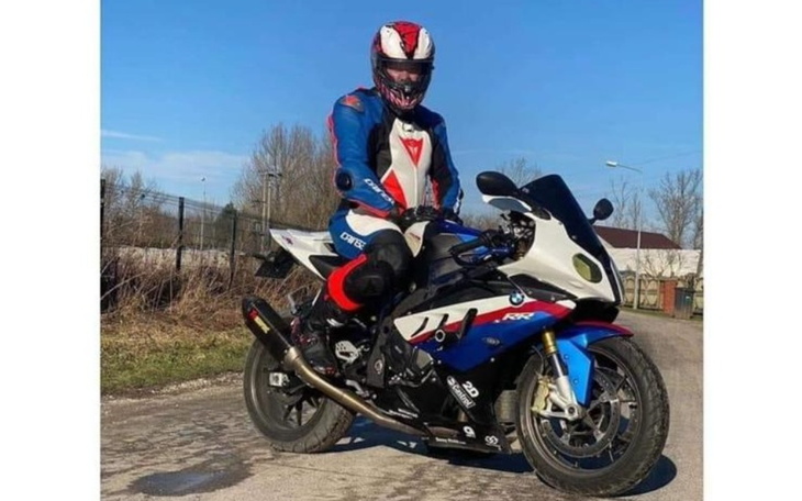 Motocyklista w kasku stoi obok sportowego motocykla.
