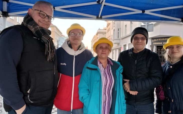 Grupa ludzi pod namiotem, wszyscy w żółtych kapeluszach.