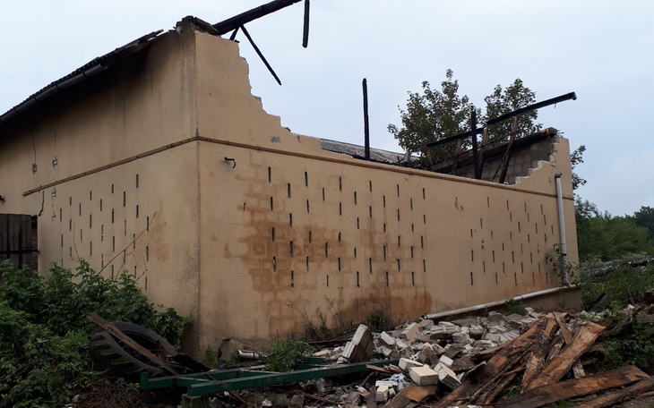 Zniszczony budynek z uszkodzoną ścianą i gruzem wokół.