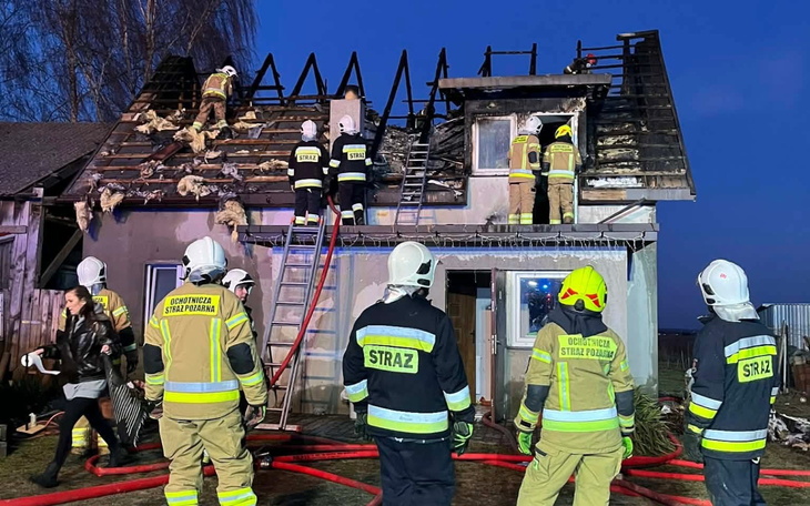 Strażacy gaszą pożar na dachu budynku w nocy.