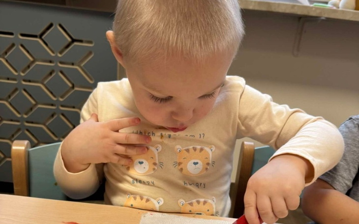 Mały chłopiec bawiący się przy stole, skupiony na pracy.