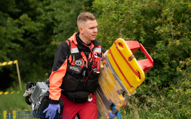 Ratownik niosący nosze w terenie.