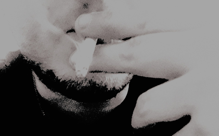 Mężczyzna trzymający papierosa, zbliżenie na twarz.