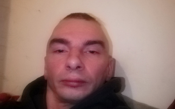 Mężczyzna z krótkimi włosami, patrzący w kamerę.