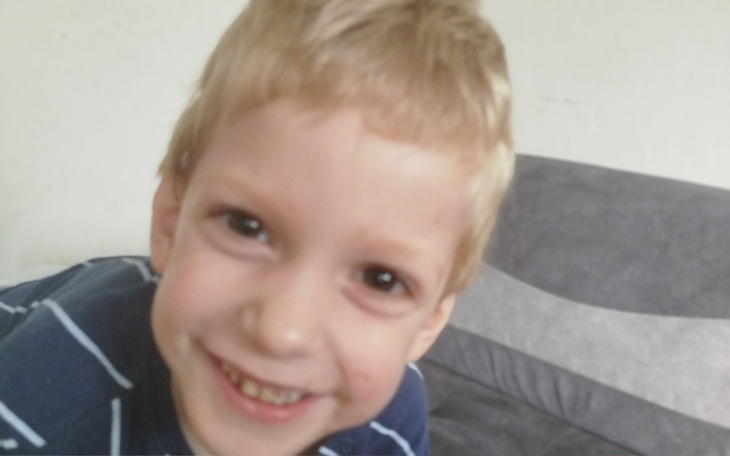 Mały chłopiec z szerokim uśmiechem, bawiący się w domu.