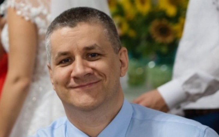 Mężczyzna w koszuli, uśmiechający się do kamery.
