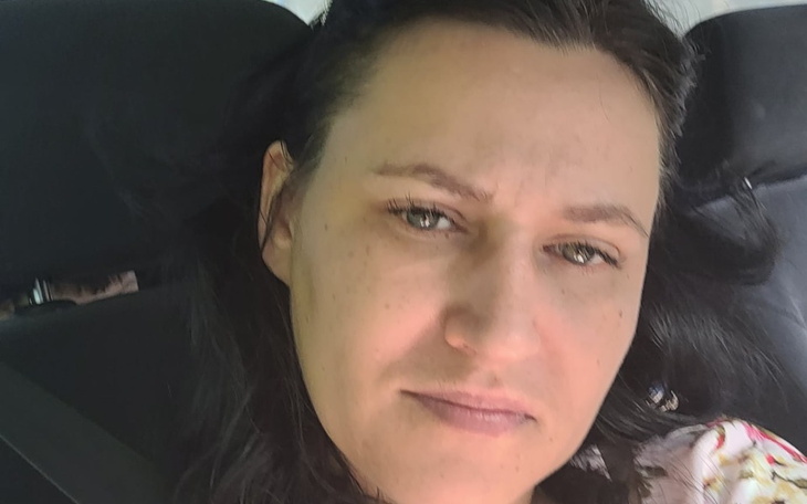 Kobieta w samochodzie, z wyrazem twarzy pełnym refleksji.