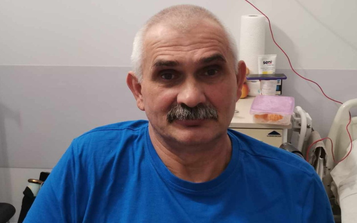 Mężczyzna w niebieskiej koszulce, siedzący w szpitalu.