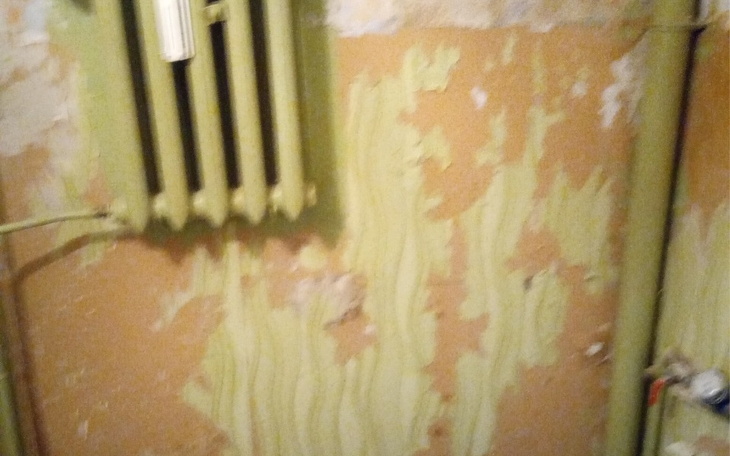 Zniszczona ściana z widocznymi śladami wilgoci i farby.