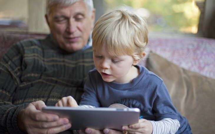 Dziadek z wnuczkiem, wspólnie korzystający z tabletu.