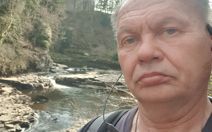 Mężczyzna na tle malowniczego krajobrazu nad rzeką.