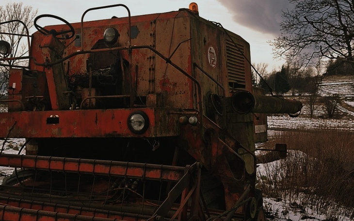 Stary traktor na polu, zniszczony przez czas.