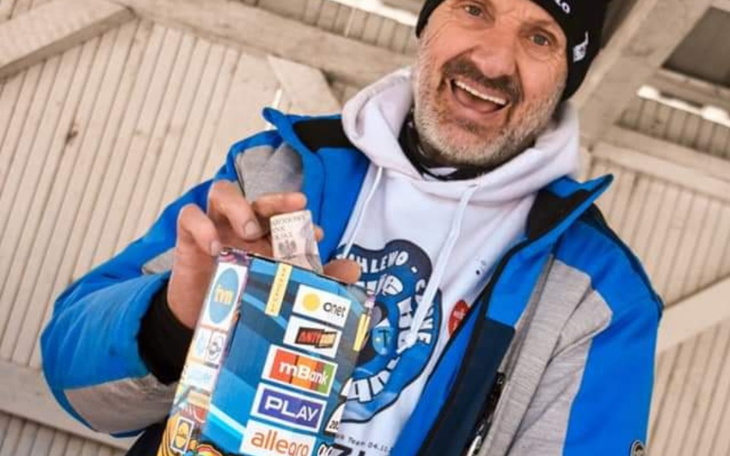 Mężczyzna trzyma puszkę z naklejkami i uśmiecha się.