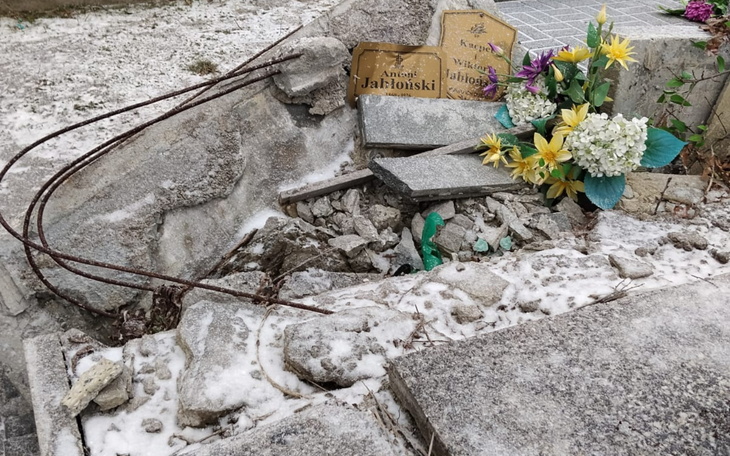 Zniszczony nagrobek z kwiatami na cmentarzu.