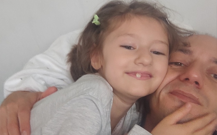 Uśmiechnięta dziewczynka przytulająca się do ojca.