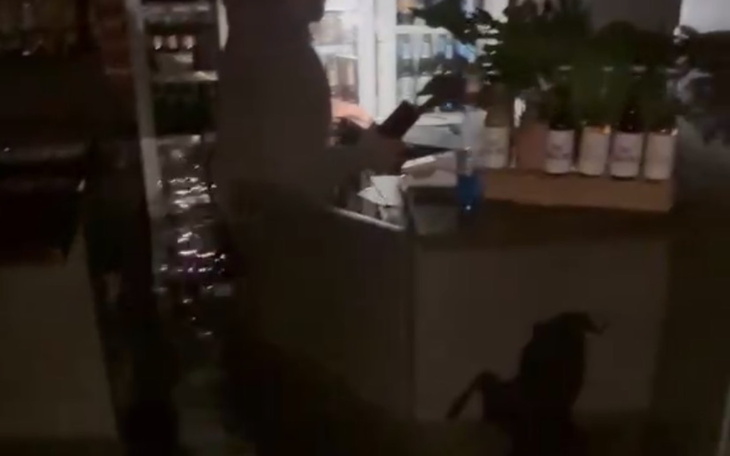 Osoba w sklepie, trzymająca przedmioty w ciemnym otoczeniu.