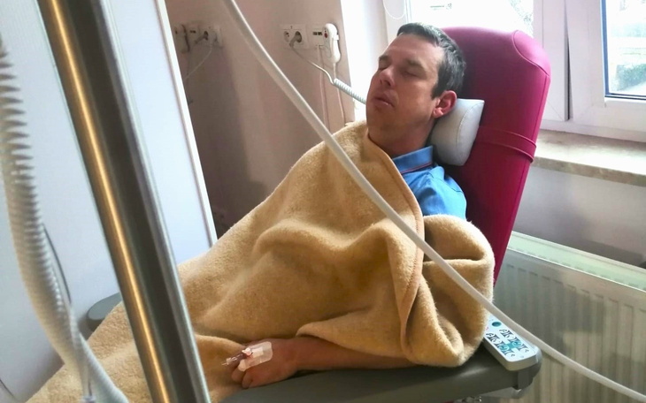 Mężczyzna w szpitalu, przykryty kocem, w stanie spoczynku.