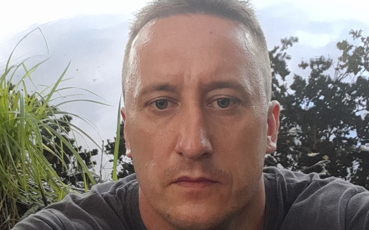 Mężczyzna z poważnym wyrazem twarzy, patrzący w stronę kamery.