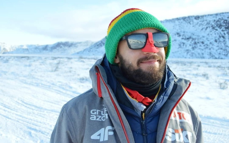 Mężczyzna w zimowej scenerii, z kolorową czapką i okularami.