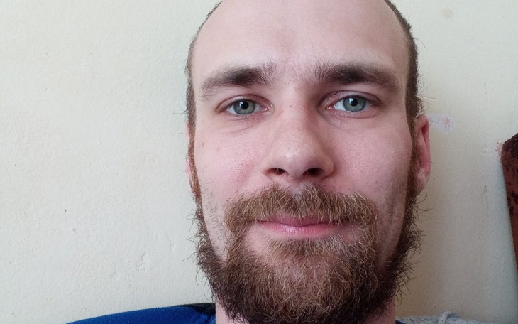 Mężczyzna z brodą i niebieskimi oczami, uśmiechający się do kamery.