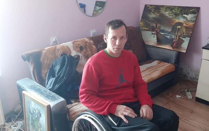 Mężczyzna na wózku inwalidzkim siedzący na kanapie w pokoju.