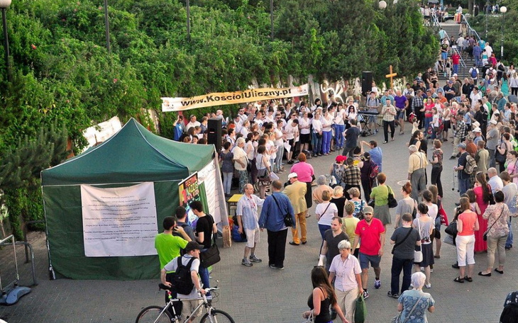 Tłum ludzi na wydarzeniu, z namiotem i występem na żywo.