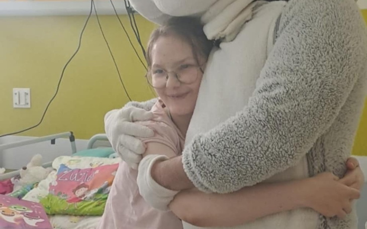 Dziecko przytulające się do postaci w kostiumie w szpitalu.