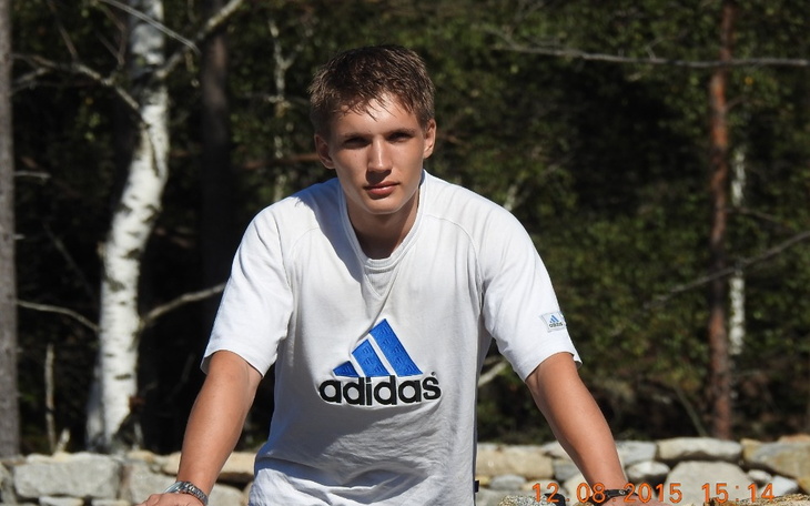 Młody mężczyzna pozujący na tle przyrody.