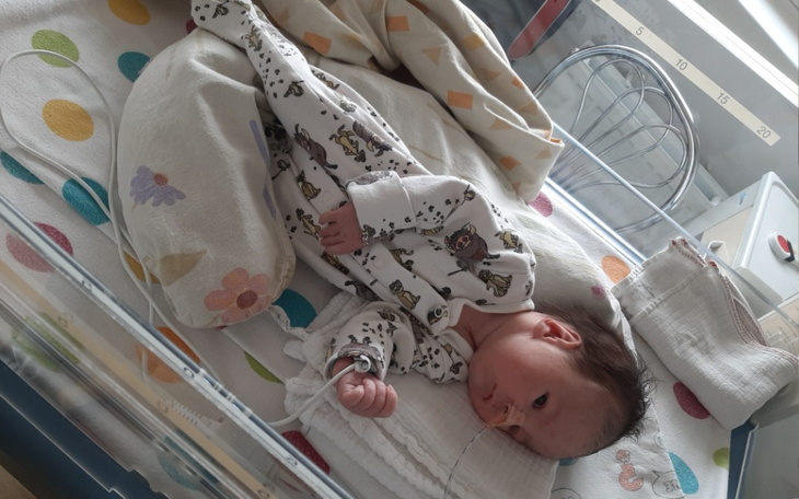 Noworodek w szpitalnym łóżeczku, otulony w kolorowe kocyki.