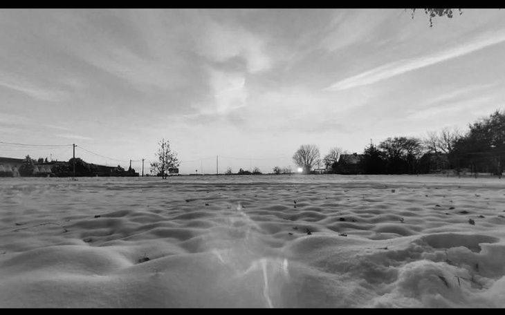 Zimowy krajobraz pokryty śniegiem, z drzewami w tle.