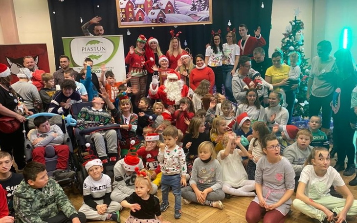 Grupa dzieci i dorosłych w świątecznych strojach na wydarzeniu.