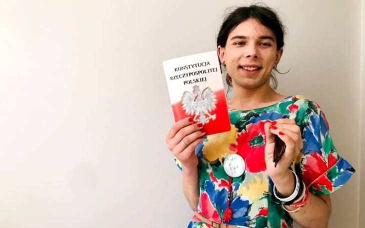 Osoba trzymająca książkę o Konstytucji w kolorowej sukience.