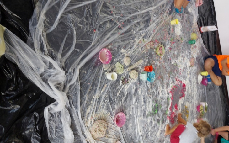 Dzieci bawiące się w artystycznym bałaganie na podłodze.